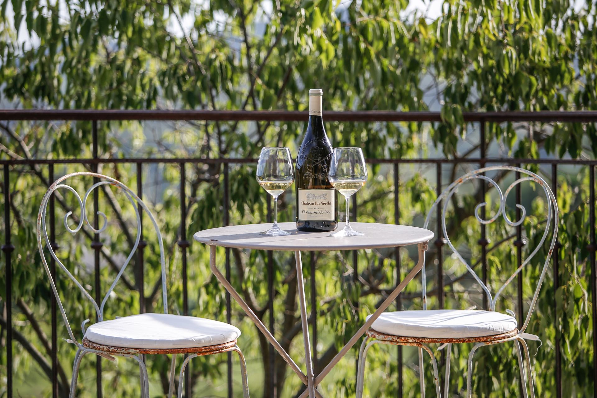 A pedestal table, a bottle of French red wine, two glasses